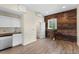 A modern open concept living room with kitchenette, wooden accent wall, and wood-look floors at 12424 Sw 140Th Loop, Dunnellon, FL 34432