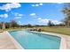 Inviting pool and spa with stone surround and outdoor seating, set against a picturesque landscape and blue skies at 12424 Sw 140Th Loop, Dunnellon, FL 34432