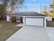 Modern one-story home featuring a large driveway and a two-car garage, set against a clear blue sky at 13384 Sw 105 Pl, Dunnellon, FL 34432