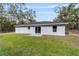 View of the backyard featuring the home's exterior, showing a well-manicured lawn surrounded by mature trees at 13396 Sw 105 Pl, Dunnellon, FL 34432