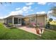 Spacious backyard with a screened lanai, open patio, lush lawn, and well-maintained landscaping at 13751 Se 88Th Ct, Summerfield, FL 34491