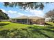 Expansive backyard view featuring lush green lawns, a screened lanai, and a comfortable patio area at 13751 Se 88Th Ct, Summerfield, FL 34491