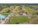 Aerial view of a lush golf course with putting green and golf carts at 13751 Se 88Th Ct, Summerfield, FL 34491