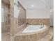Elegant bathroom featuring a luxurious tub and glass-enclosed shower with tan tiling at 13920 Ne 38Th Ave, Anthony, FL 32617
