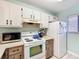 Bright kitchen featuring white appliances and upper cabinets with lower rustic wood accents at 3650 Ne 21St St, Ocala, FL 34470