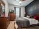 A comfortable bedroom featuring a dark accent wall, window with blinds, and wooden dresser, providing a serene and private space at 5021 Sw 88Th St, Ocala, FL 34476