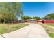 Exterior view of a single-story home with a long driveway, lawn, and a red fence at 5041 Ne 4Th St, Ocala, FL 34470