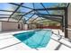 View of a pool with screened enclosure, concrete pool deck, ladders, and steps into the water at 5041 Ne 4Th St, Ocala, FL 34470