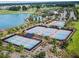 Aerial view of the tennis and pickleball courts with a lake, pool, and golf course in the background at 5563 Nw 40Th Pl, Ocala, FL 34482