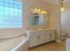 Bathroom with double sinks, marble countertops, and a soaking tub at 5916 Nw 27Th Pl, Ocala, FL 34482