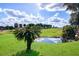 Scenic golf course view with a pond and palm trees, set against a backdrop of a blue sky at 5916 Nw 27Th Pl, Ocala, FL 34482
