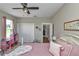 Bedroom featuring a ceiling fan, closet, window with curtains, neutral walls and a bed with pink bedding at 7432 Ne 26Th Ave, Ocala, FL 34479