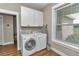 Efficient laundry room with modern washer and dryer, storage cabinets, and natural light at 7432 Ne 26Th Ave, Ocala, FL 34479