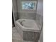 This bathroom shows a relaxing white garden tub encased in ceramic tile and a window for natural light at 7677 Sw 81St Pl, Ocala, FL 34476