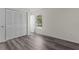 This bedroom features wood-look flooring, a window with wooded views, and a closet with white, louvered doors at 9607 Se 122Nd Pl, Belleview, FL 34420