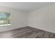 This bedroom features wood-look flooring, a window with wooded views, and neutral-colored walls at 9607 Se 122Nd Pl, Belleview, FL 34420
