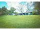 Large backyard with lush green grass, mature trees and a shed is ideal for outdoor activities and relaxation at 9795 Ne 303Rd Ave, Salt Springs, FL 32134