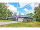 Charming exterior of the home features a well-manicured lawn, neutral paint, a two-car garage, and beautiful landscaping at 9795 Ne 303Rd Ave, Salt Springs, FL 32134