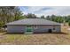 Rear exterior of the house showcasing a sliding glass door, windows, a well-maintained lawn, and the surrounding environment at 10069 Sw 140Th Ave, Dunnellon, FL 34432