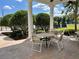 Covered outdoor community patio with tables and chairs surrounded by lush greenery and landscaping at 13686 Sw 111Th Ave, Dunnellon, FL 34432