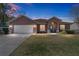 Inviting single-story home featuring a lush green lawn and attached two car garage at 16272 Se 89Th Ct, Summerfield, FL 34491