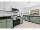 Modern kitchen with stainless steel appliances, green cabinets, and ample counter space at 1818 Se Lake Weir Ave, Ocala, FL 34471