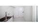 Functional laundry room with a utility sink, storage shelf, and access to the exterior at 19 Juniper Pass, Ocala, FL 34480