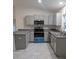 A well-equipped kitchen featuring gray cabinets, stainless steel appliances, and tile flooring at 261 Locust Pass Loop, Ocala, FL 34472