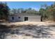 The backyard of the property has gray siding, a black roof, sliding glass doors, and a concrete patio at 29 Fisher Ter, Ocklawaha, FL 32179