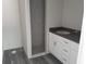 The bathroom features a tiled walk-in shower, dark countertop, modern sink, and gray wood-look flooring at 29 Fisher Ter, Ocklawaha, FL 32179