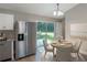 Bright dining area with a table for four, stainless steel refrigerator, and a sliding glass door to the backyard at 29 Fisher Ter, Ocklawaha, FL 32179