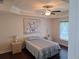 Comfortable main bedroom with ceiling fan, tray ceiling, dark floors, and natural light at 3819 Se 99Th St, Belleview, FL 34420