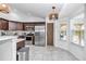 Bright kitchen features stainless appliances, brown cabinets, a tiled floor, and modern light fixtures at 5620 Sw 172Nd Loop, Ocala, FL 34473