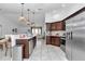 Open kitchen with stainless steel appliances, brown cabinets, a large island, and views into the living room at 5620 Sw 172Nd Loop, Ocala, FL 34473