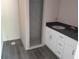 Well-lit bathroom with gray tiled shower and white vanity with black countertop at 59 Fisher Ct, Ocklawaha, FL 32179