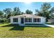 Charming single-story home featuring a well-manicured lawn, neutral siding, dark shutters, and inviting front entrance at 59 Fisher Ct, Ocklawaha, FL 32179
