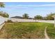 Wide shot of the spacious back yard with a vinyl fence, green grass, and tropical trees at 8330 Se 161St St, Summerfield, FL 34491
