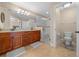 Bright bathroom featuring dual sinks, wood cabinetry, granite countertops, and a glass enclosed walk-in shower at 9436 Se 163Rd St, Summerfield, FL 34491