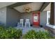 Charming front porch features rocking chairs, ceiling fan, and a bright red front door at 9436 Se 163Rd St, Summerfield, FL 34491