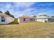 Spacious backyard with lawn, showcasing the home's rear facade and the surrounding neighborhood, under a blue, cloudy sky at 9575 Sw 92Nd Street Rd, Ocala, FL 34481