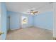 Simple bedroom with blue walls, carpeted floor, ceiling fan, and a window that lets in natural light at 9575 Sw 92Nd Street Rd, Ocala, FL 34481