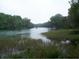 Picturesque water view with a distant boat, set amidst a backdrop of trees and natural beauty at 9610 Sw 198Th Cir, Dunnellon, FL 34432