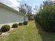 Well-maintained side yard with green grass, bushes, and an HVAC unit at 9610 Sw 198Th Cir, Dunnellon, FL 34432