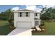 Two-story home with light gray siding, a two-car garage, manicured lawn, and stylish architectural details at 2170 Ne 28Th Ln, Ocala, FL 34470