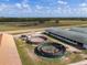 Aerial of horse exercise rings and stables, alongside equipment storage, offering full equestrian amenities at 4695 Ne 112Th Ln, Anthony, FL 32617