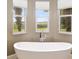 Bright bathroom featuring a standalone tub beneath three windows that provide relaxing views of the green outdoors at 4695 Ne 112Th Ln, Anthony, FL 32617