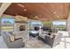 Covered patio with stone fireplace, travertine floors, ceiling fans, and comfortable seating overlooking the pasture at 4695 Ne 112Th Ln, Anthony, FL 32617