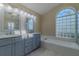Bathroom with double vanities, jetted tub, and a glass block window at 5115 Nw 21St Loop, Ocala, FL 34482