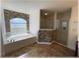 Bright bathroom showcases a luxurious soaking tub with stone accent wall and a glass-enclosed shower, exuding spa-like elegance at 6307 Se 8Th Ln, Ocala, FL 34472