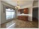 Dining area with wood cabinets, granite countertop, chandelier, and decorative window at 6307 Se 8Th Ln, Ocala, FL 34472